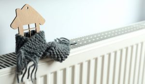 Drvena kućica obmotana šalom na radijatoru