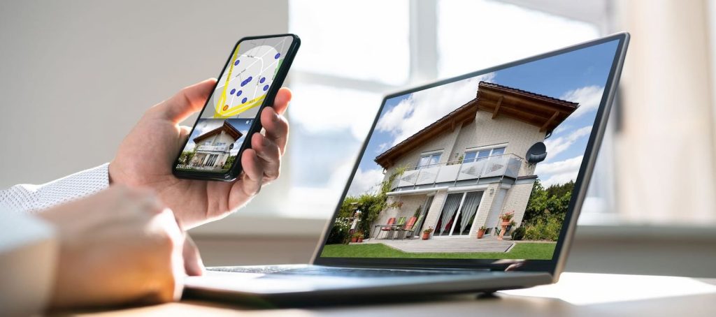 Osoba pretražuje nekretnine na telefonu i laptopu