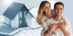 Zagrljeni mladi par sa kalkulatorom stambenih kredita u pozadini