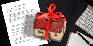 Model kuće sa mašnom i ugovor o poklonu na radnom stolu